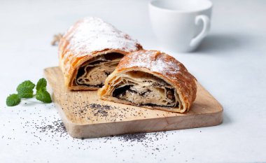 Strudel haşhaş tohumu ve hafif bir arka plan üzerine kuru üzüm ile