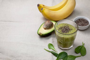 Smoothies avokado muz ıspanak bir cam, muz ve avokado, chia tohumu keten bir arka plan üzerinde