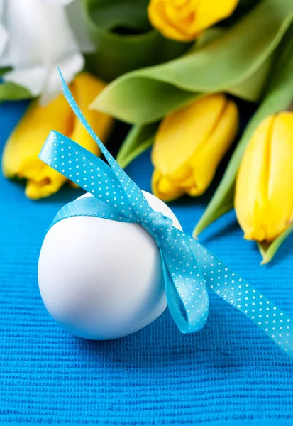 Vejce Velikonoční Bílé Modrou Stužkou Žluté Tulipány Modrém Pozadí — Stock fotografie