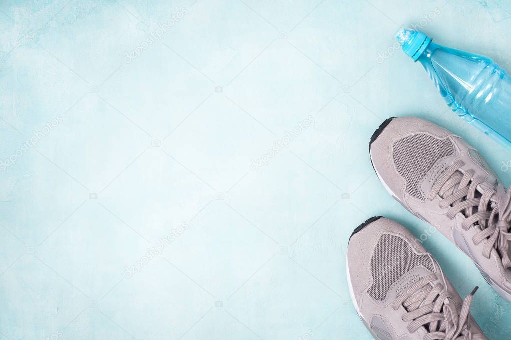 Gray sneakers and a bottle of water on a blue background. view from above. toning