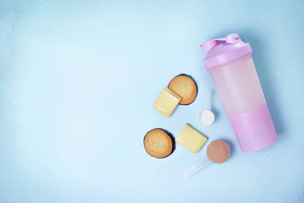 shake with protein drink, protein powder, protein bars and protein cookies on a blue background. view from above. copy space