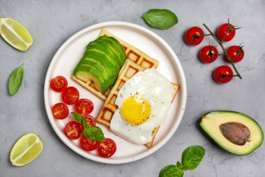 sağlıklı kahvaltı. avokado, sahanda yumurta, domates gri beton zemin üzerine Belçika gofret. yukarıdan görüntülemek