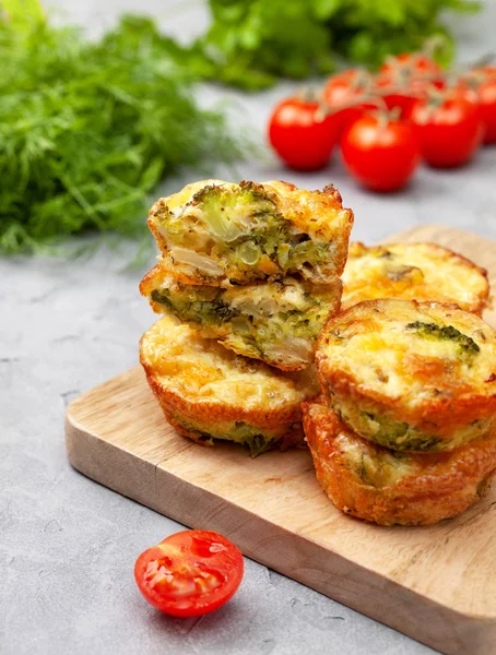 sağlıklı kahvaltı. Brokoli peynir alıntılar (kek), taze domates, hafif beton zemin üzerine taze otlar. Aperatif keto diyet için