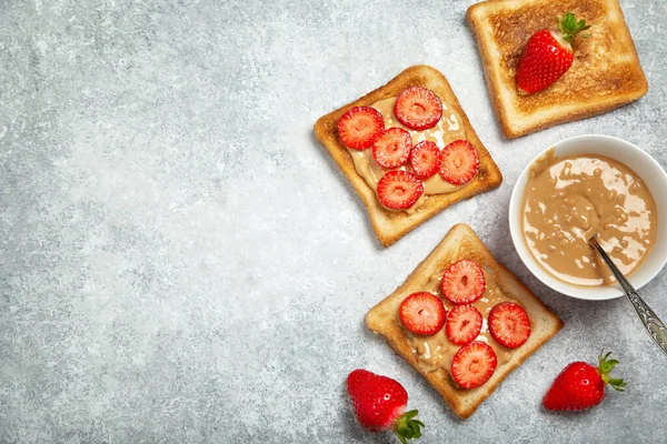ピーナッツバターと新鮮なイチゴを灰色の背景でトースト 上からの眺め ロイヤリティフリーのストック写真
