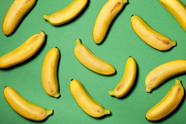 緑色の紙の背景に小さな黄色のバナナ 上からの眺め ストック写真