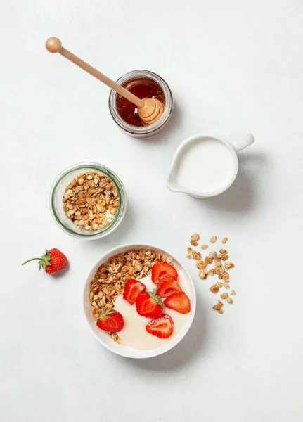 健康的な朝食の概念です 白い背景の白いボウルにグラノーラ ギリシャヨーグルト イチゴと朝食 上からの眺め ロイヤリティフリーのストック写真