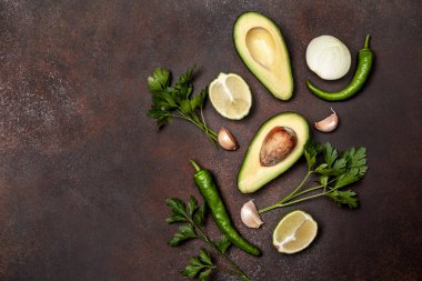 Guacamole için taze malzemeler: avokado, chili, kahverengi arka planda limon. Yukarıdan bak. Boşluğu kopyala