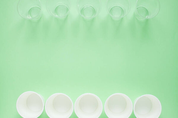 Макет на зеленом фоне из белой бумаги и пластиковых одноразовых чашек. Забота об окружающей среде. Переработка и сортировка мусора. Одноразовая посуда. Загрязнение окружающей среды
.