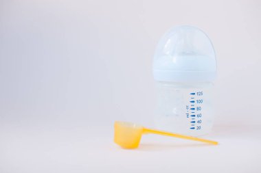 Bebeklerin yapay beslenmesi. Karışım için şişe, ölçü kaşığı, kurutulmuş süt karışımı. Pastel renklerde silikon kemirgen. Metin için alanı kopyala.