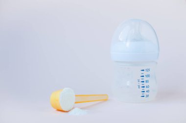 Bebeklerin yapay beslenmesi. Karışım için şişe, ölçü kaşığı, kurutulmuş süt karışımı. Pastel renklerde silikon kemirgen. Metin için alanı kopyala.