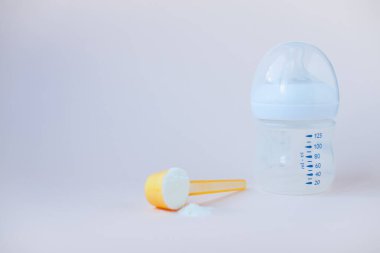 Bebeklerin yapay beslenmesi. Karışım için şişe, ölçü kaşığı, kurutulmuş süt karışımı. Pastel renklerde silikon kemirgen. Metin için alanı kopyala.