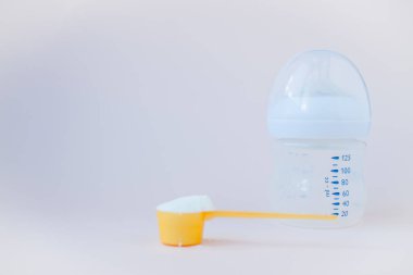 Bebeklerin yapay beslenmesi. Karışım için şişe, ölçü kaşığı, kurutulmuş süt karışımı. Pastel renklerde silikon kemirgen. Metin için alanı kopyala.