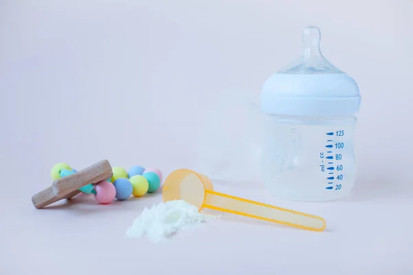 Bebeklerin yapay beslenmesi. Karışım için şişe, ölçü kaşığı, kurutulmuş süt karışımı. Pastel renklerde silikon kemirgen. Metin için alanı kopyala.