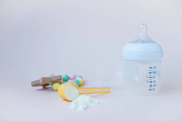 Bebeklerin yapay beslenmesi. Karışım için şişe, ölçü kaşığı, kurutulmuş süt karışımı. Pastel renklerde silikon kemirgen. Metin için alanı kopyala.