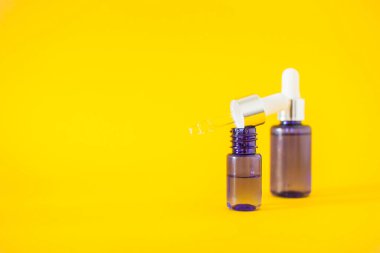 Sarı arka planda serum bulunan kozmetik şişeler. Kozmetik ve güzellik kavramı.