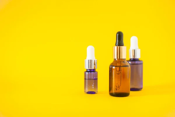Frascos cosméticos con suero sobre fondo amarillo. Cosmetología y concepto de belleza. —  Fotos de Stock