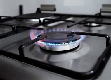 Gaz sobası, mavi ve kırmızı alevli. Modern mutfak siyah ve gümüş ocak ve gaz açık. Benzin aralığı alev alev yanıyor. Yakıt ocağına yakından bak. 
