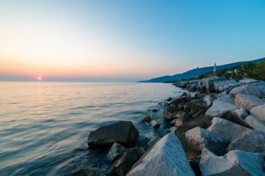 Trieste, Friuli Venezia Giulia, İtalya'nın deniz feneri altında sahilde günbatımı
