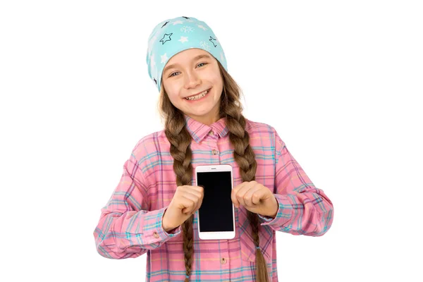 Rolig liten flicka visar smart telefon med blank skärm isolerad på vit bakgrund. Spela spel och titta på video. Stockbild