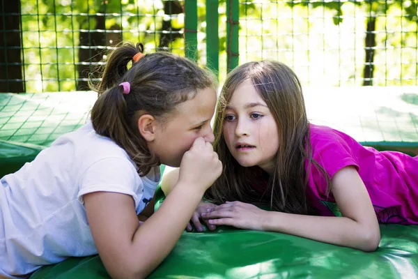 Две Девушки Рассказывают Секрет Лежат Батуте Открытом Воздухе Зеленом Парке — стоковое фото