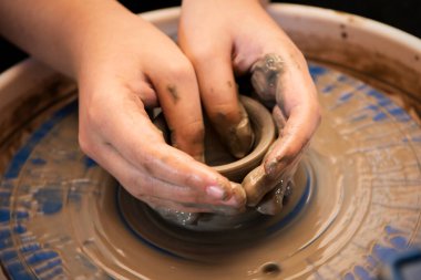 Çocuk elleri seramik çanak çömlek çarkında bir kap şekillendiriyor..