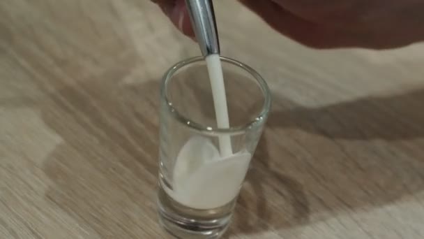 Barman verser de la liqueur de crème d'un grand verre à un verre à cocktail 