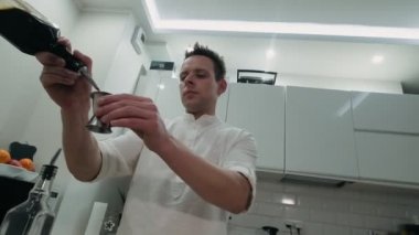 Barmen Jigger 'a kahve likörü döker ve barın üzerine cam şişe koyar.