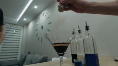 Barmen yanan bir alkollü kokteylin üzerine tarçın serper.