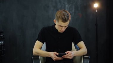 Çatı katındaki genç adam akıllı telefon kullanır ve video röportajına hazırlanır.