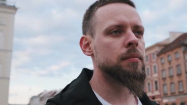 Yakışıklı, sakallı, ciddi bir gencin yakın portresi.