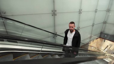 Bagajı olan adam yürüyen merdivende ilerliyor. Metro metro istasyonu