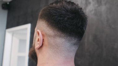 Kuaförde saç kesiminden sonra poz veren genç bir adam. Kapat.