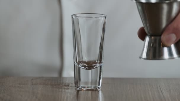 Le barman verse la sambuca du jigger au verre à cocktail. Gros plan