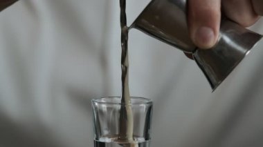 Barmen jigger 'dan kokteyl bardağına sambuca ile İrlanda kreması döker.