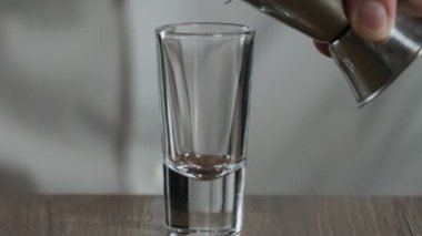 Barmen Jigger 'dan kokteyl bardağına sambuca doldurur.