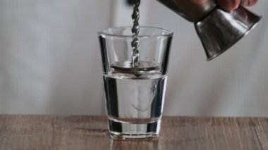 Barmen Jigger 'dan kokteyl bardağına sambuca doldurur.