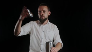 Barmen kokteyli sallıyor. Barmen kokteylde içki karıştırıyor.