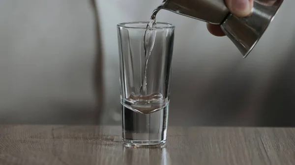 Barmen Jigger 'dan kokteyl bardağına sambuca dolduruyor. Kapat.