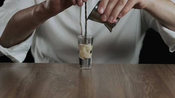 Barmen jigger 'dan kokteyl bardağına sambuca ile İrlanda kreması döker.