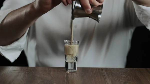 Barmen jigger 'dan kokteyl bardağına sambuca ile İrlanda kreması döker.