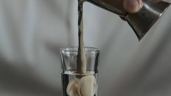 Barmen jigger 'dan kokteyl bardağına sambuca ile İrlanda kreması döker.