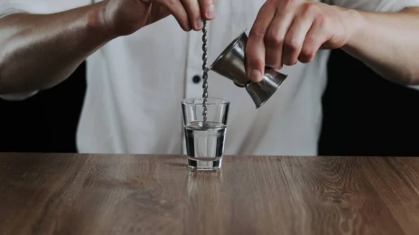 Barmen Jigger 'dan kokteyl bardağına sambuca doldurur.