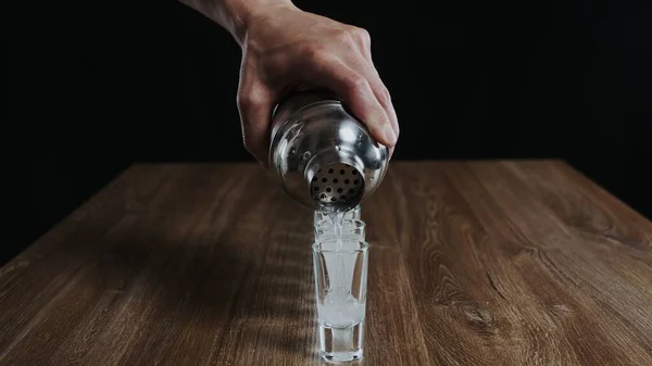 Barmen kadehten bardağa kamikaze alkollü kokteyli dolduruyor.