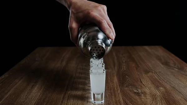 Barmen kadehten bardağa kamikaze alkollü kokteyli dolduruyor.