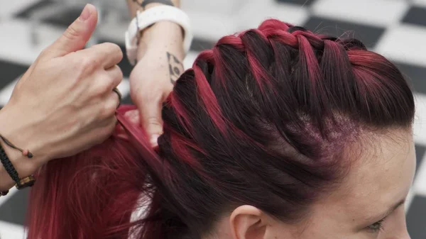 赤い色の女性の髪に編組を果たしているプロの美容師 — ストック写真
