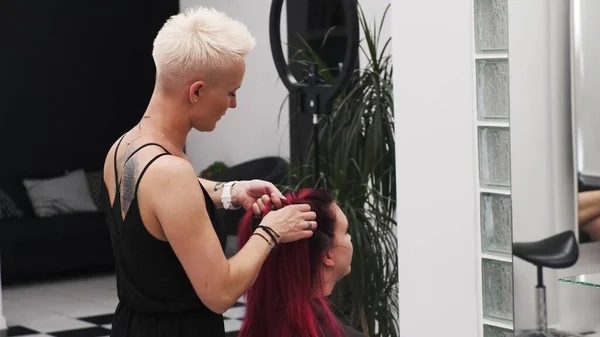 SAVAŞ, POLAND - 12 Haziran 2019: kızıl kadın saçlarına örgü ören kuaför