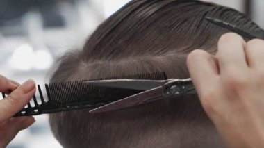 Erkek saçını tarayıp kesen profesyonel bir kadın kuaför.