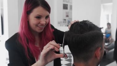 Erkek saçını tarayıp kesen profesyonel bir kadın kuaför.