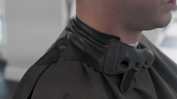 Yakışıklı adam kuaförde moda saç kesimi yaptırıyor. Stilist müşteriyi hazırlar