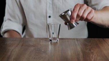 Barmen Jigger 'dan kokteyl bardağına sambuca doldurur.